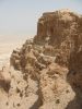 The cliffs on the east edge of Masada are about 1,300 feet (400 m) high and the cliffs on the west are about 300 feet (90 m) high; the natural approaches to the cliff top are very difficult. The top of the plateau is flat and rhomboid-shaped, about 1,800 feet (550 m) by 900 feet (275 m). There was a casemate wall around the top of the plateau totaling 4,300 feet (1.3 km) long and 12 feet (3.7 m) thick, with many towers, and the fortress included storehouses, barracks, an armory, the palace, and cisterns that were refilled by rainwater. Three narrow, winding paths led from below up to fortified gates.